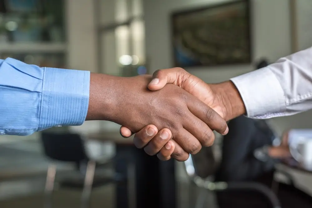 Two people shaking hands over a completed car sale